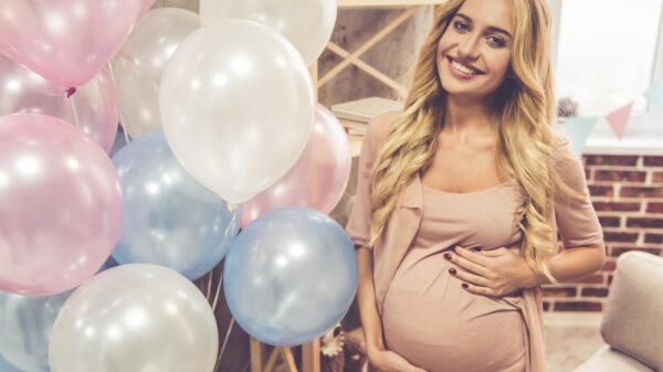 Mujer embarazada con globos rosas y azules
