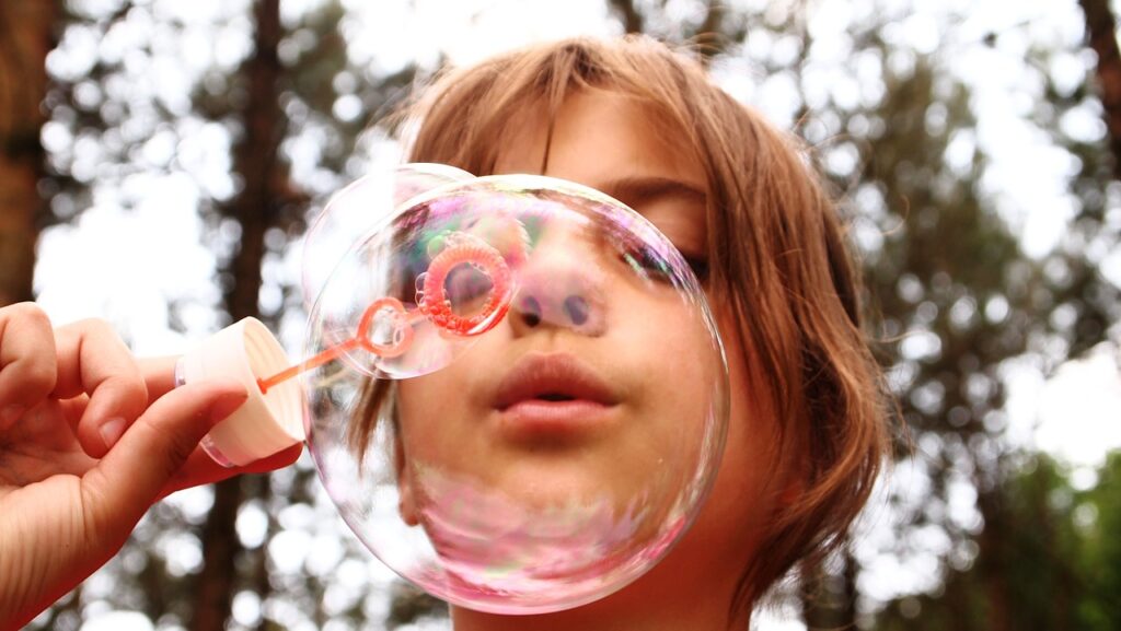 Niña jugando con burbujas. En el día del autismo